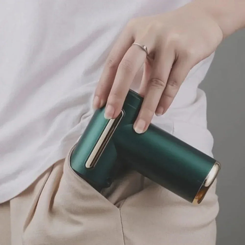 Mini secador de cabelo portátil verde metálico sendo colocado no bolso de calça bege