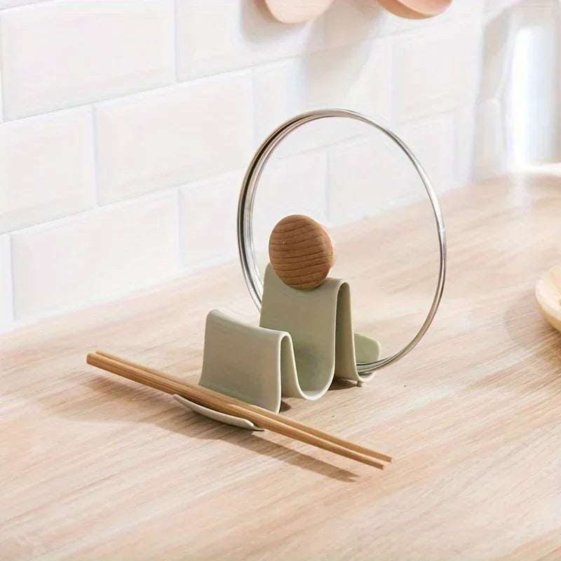 Suporte decorativo para tampas e utensílios de cozinha em formato minimalista sobre bancada de madeira.