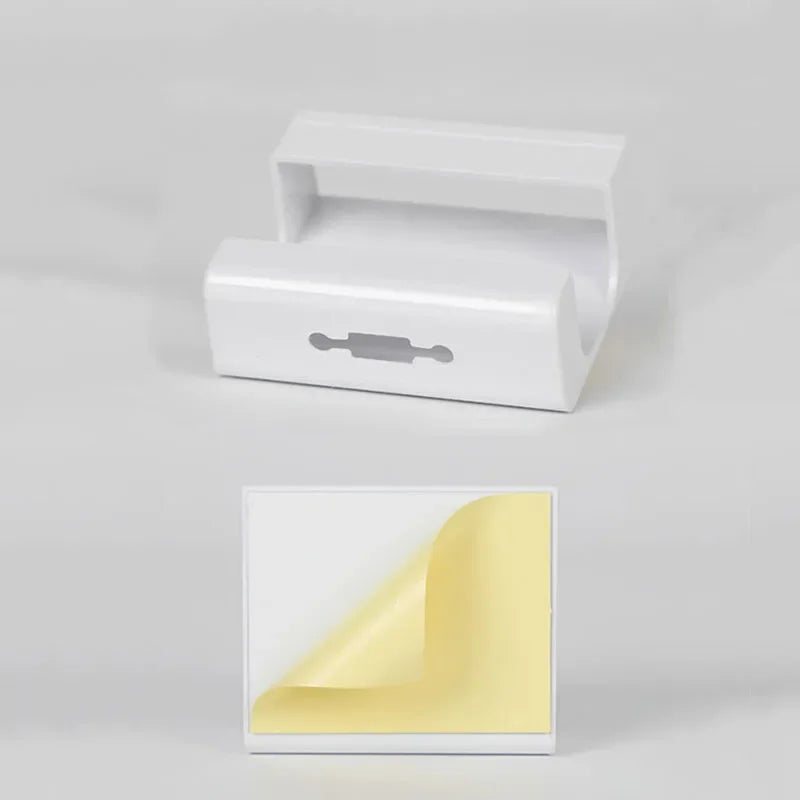 Suporte adesivo branco de parede com fita dupla face para organização, fundo cinza claro.